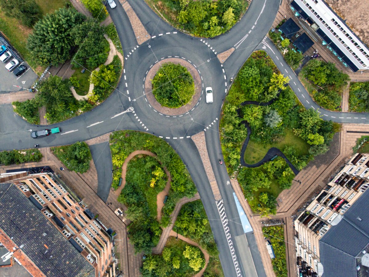 Aerial drone view of a green urban roundabout and modern infrastructure.