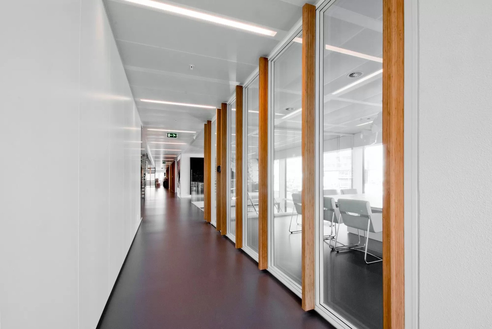 Demountable glass partitions with natural wood framing in an office corridor.